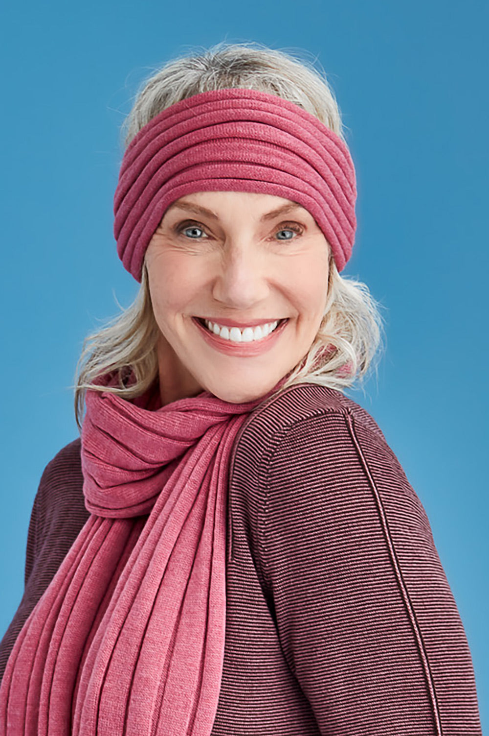 Woman wearing a pink headband and scarf against a blue background