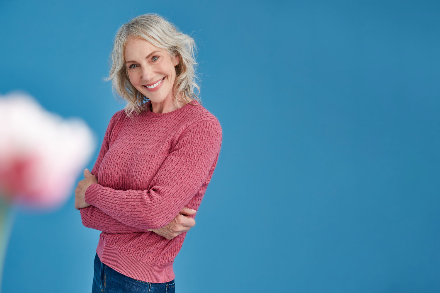 Woman wearing a pink sweater against a blue background