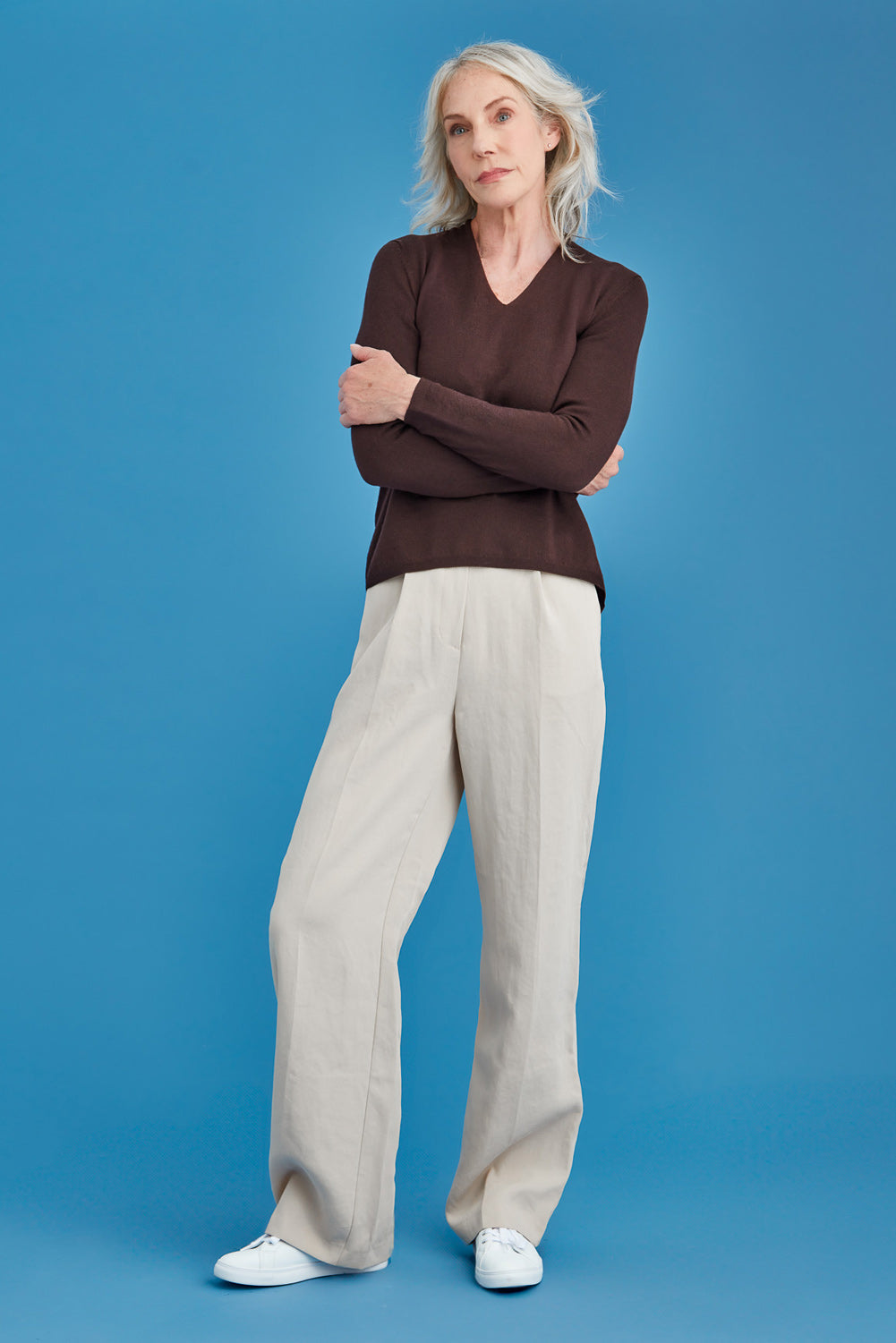 Woman wearing a brown merino sweater against a blue background