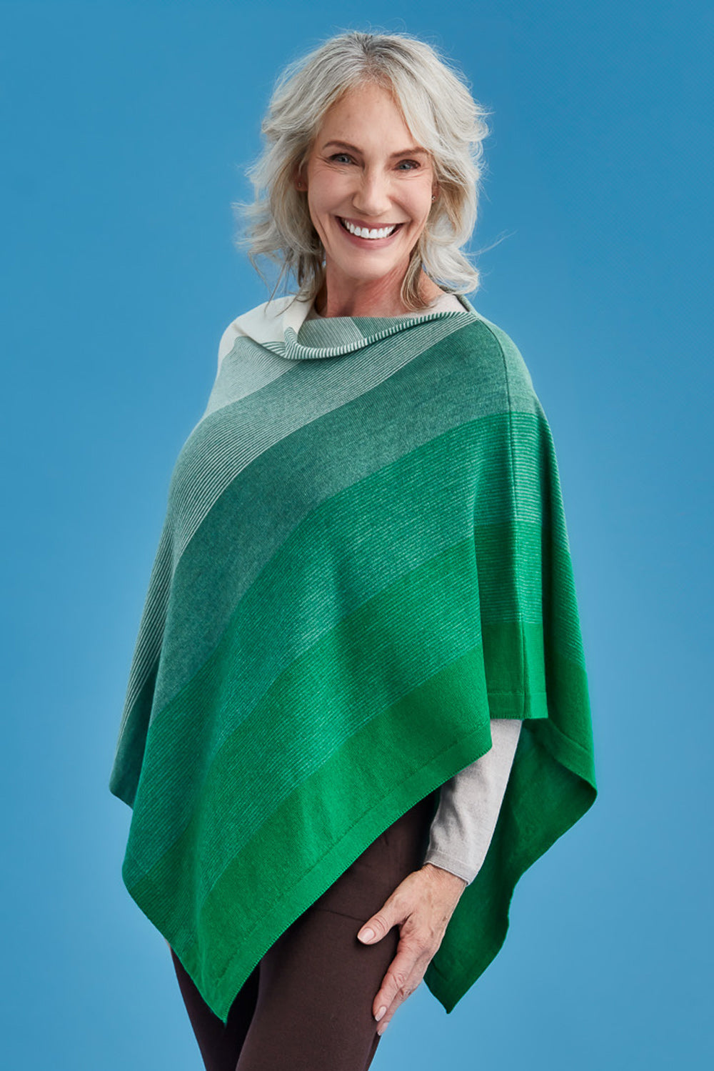 Woman wearing a green and white striped poncho against a blue background