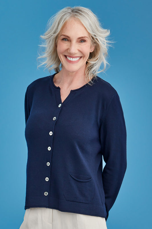 Woman wearing a navy blue cardigan with white buttons against a blue background