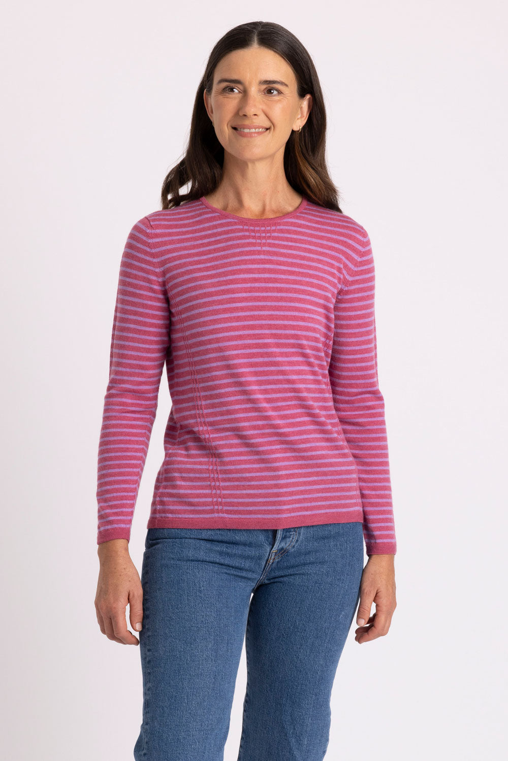 Woman wearing a pink and lavender striped sweater against a white background