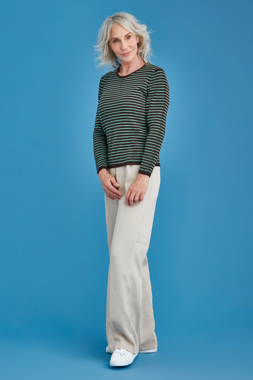 Woman wearing a green and brown striped sweater against a blue background