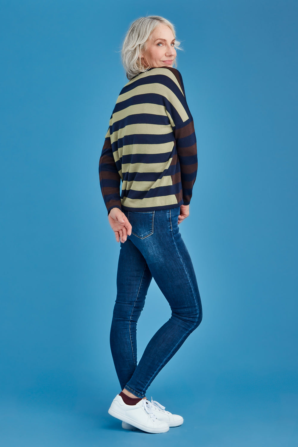 Woman wearing a striped sweater and jeans on a blue background