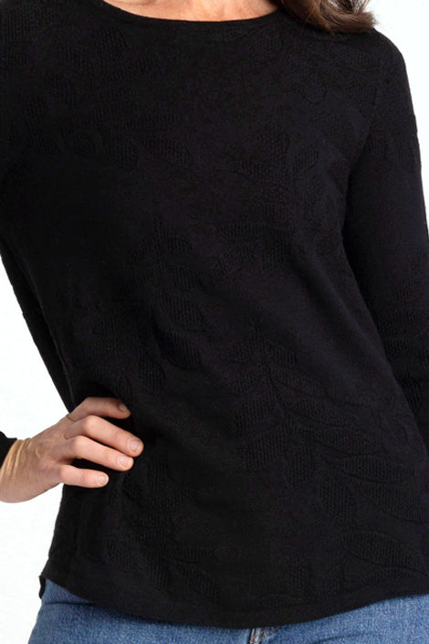 Woman wearing a black sweater with floral patterns against a white background