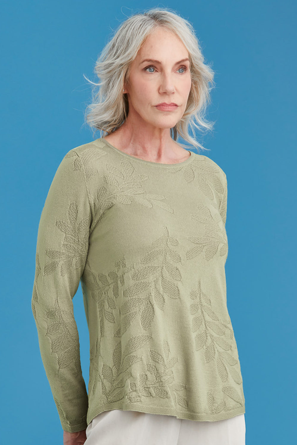 Woman wearing a light green patterned sweater against a blue background