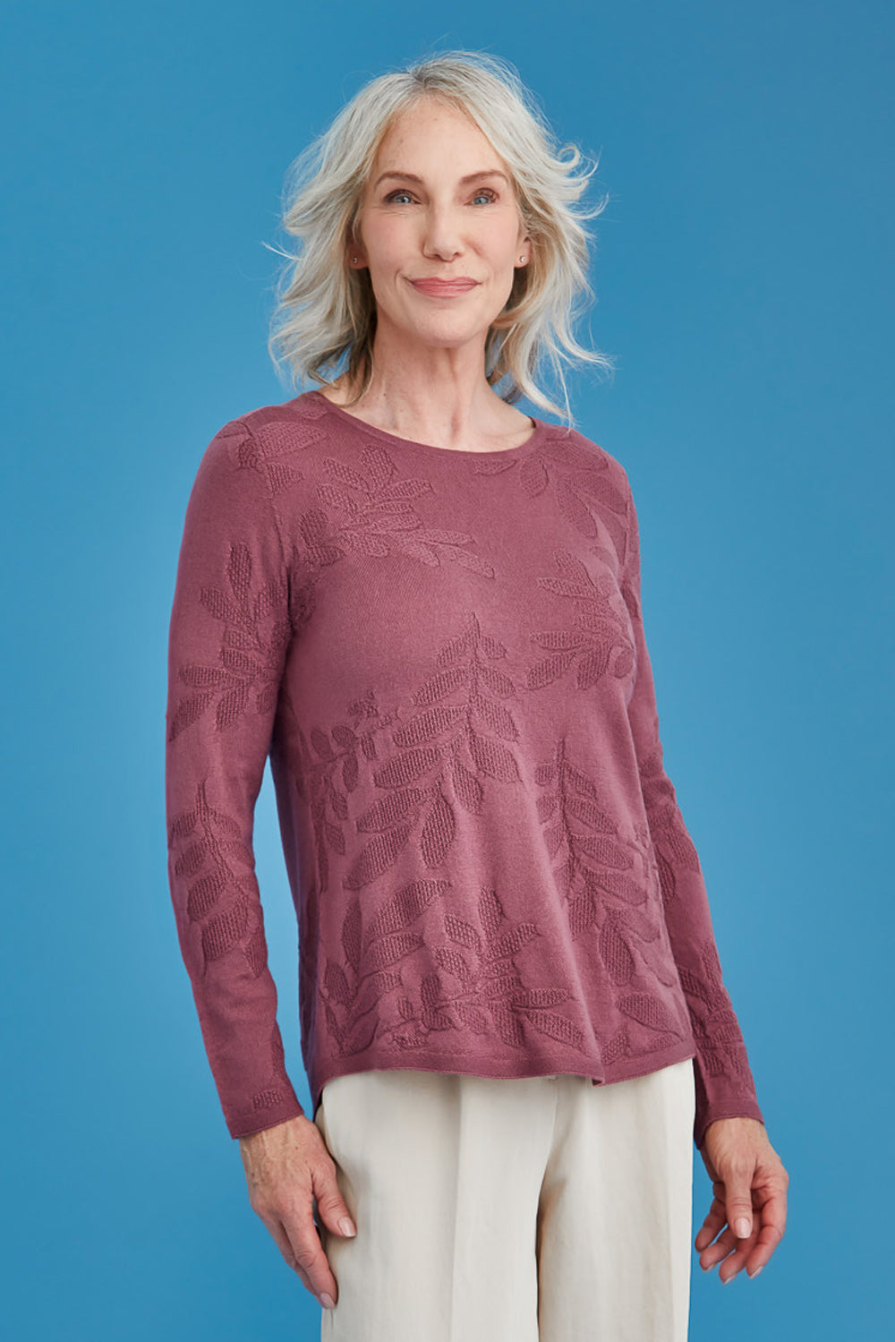 Woman wearing a maroon sweater with floral patterns against a blue background