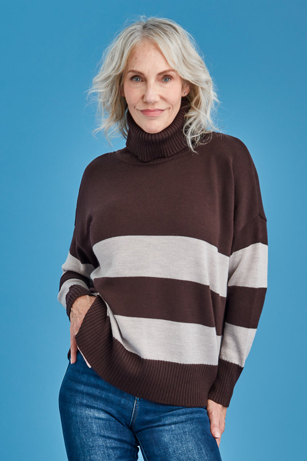 Woman wearing a brown and white striped merino sweater against a blue background